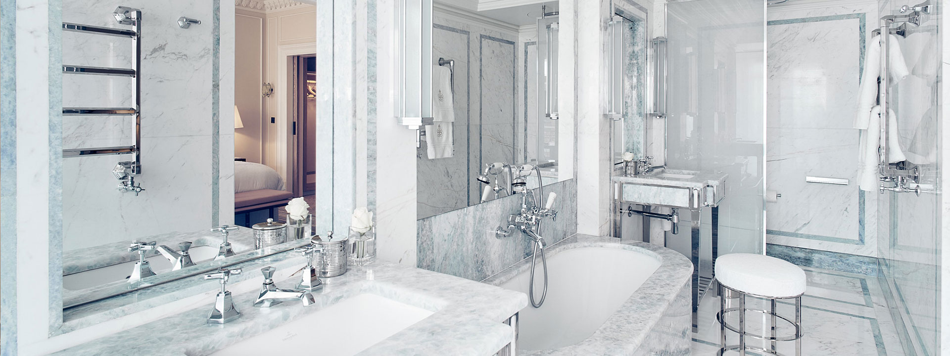 Twin basins, bath and walk-in shower in the luxurious marble design of the Mayfair Suite.