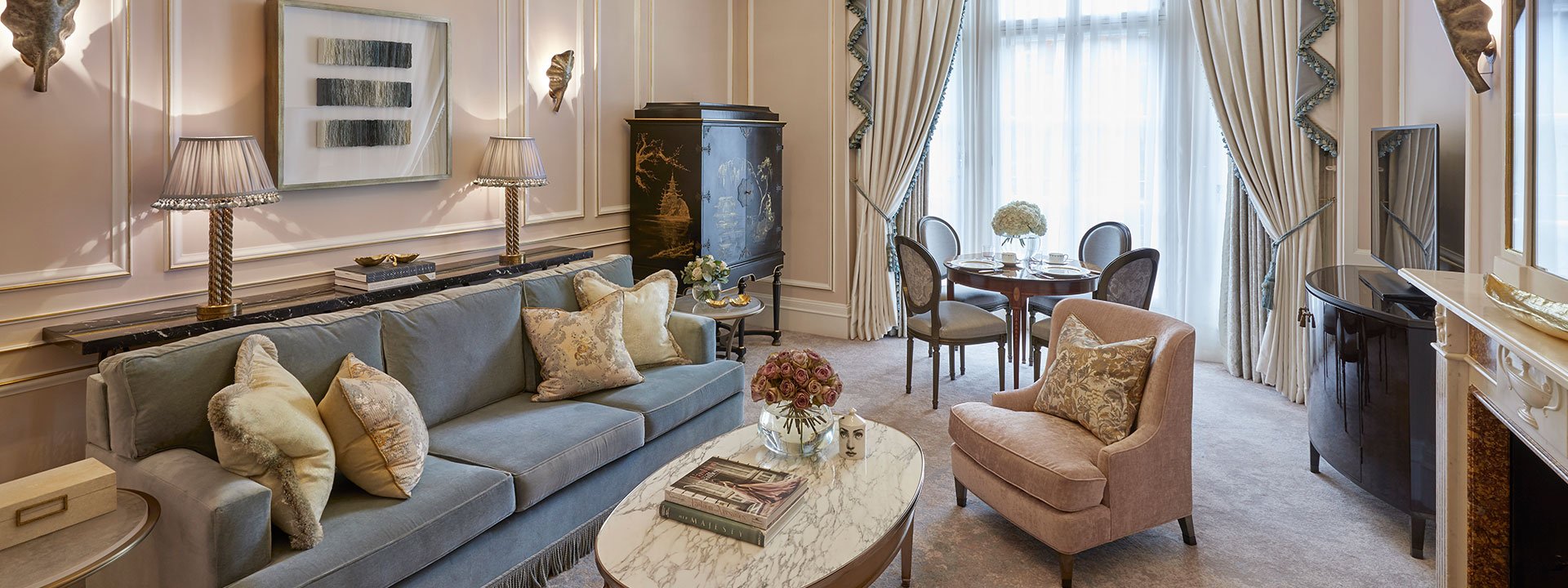 A view of the comfortable sofa and armchair in the sitting room next to the fireplace in the Mayfair Suite.