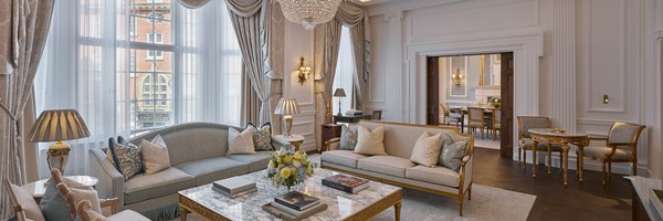 The living room of the Georgian Suite with sofas and a beautiful marble table. There is a grand chandelier on the ceiling. In the background is the dining room.