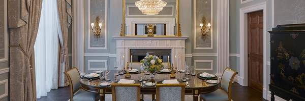 The dining table at the Georgian Suite with 6 dining chairs around, a beautiful fireplace in the background, and embroided wall paper.
