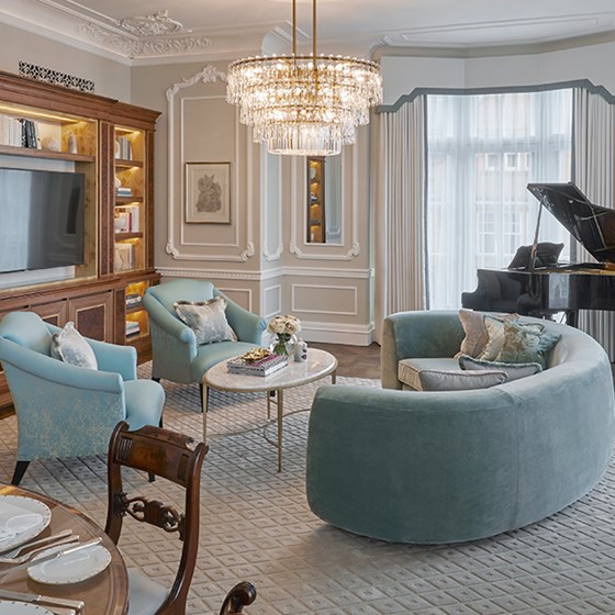 A comfortable blue sofa and armchairs, in a luxurious interior from The Grand Piano Suite at Claridge's Hotel.
