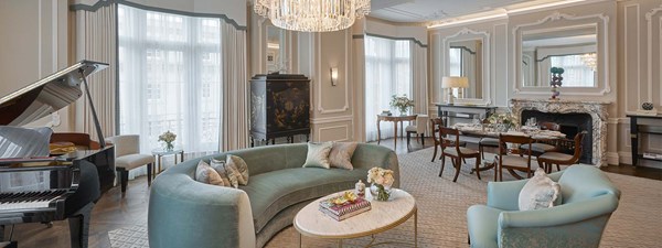 Grand Piano Suite at Claridge's - lounge area with couch and armchair, dining area with a fireplace, and grand piano on the left hand side.