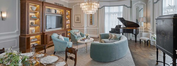 Grand Piano Suite at Claridge's - lounge area with couches and armchairs, TV on the wall, and piano in the back.
