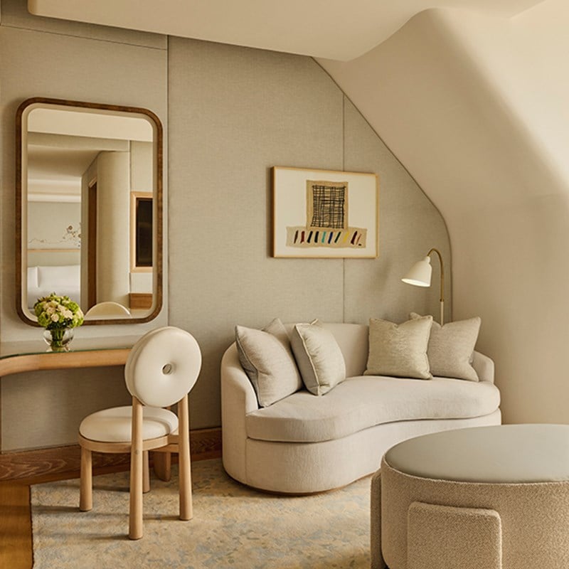 Cosy corner in the Grand Terrace Suite with a curved cream sofa, cushions, a writing desk with chair, and wall art above.