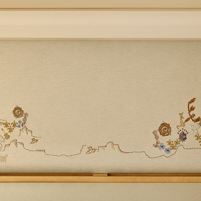 Detail of embroidered wall art in the Grand Terrace Suite showing delicate floral and nature-inspired motifs in gold, blue, and earth tones.