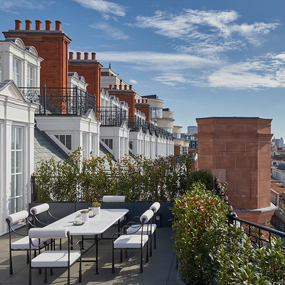 The white dining table and chairs as part of the Grand Terrace Suite, with beautiful views of the hotel's surroundings.