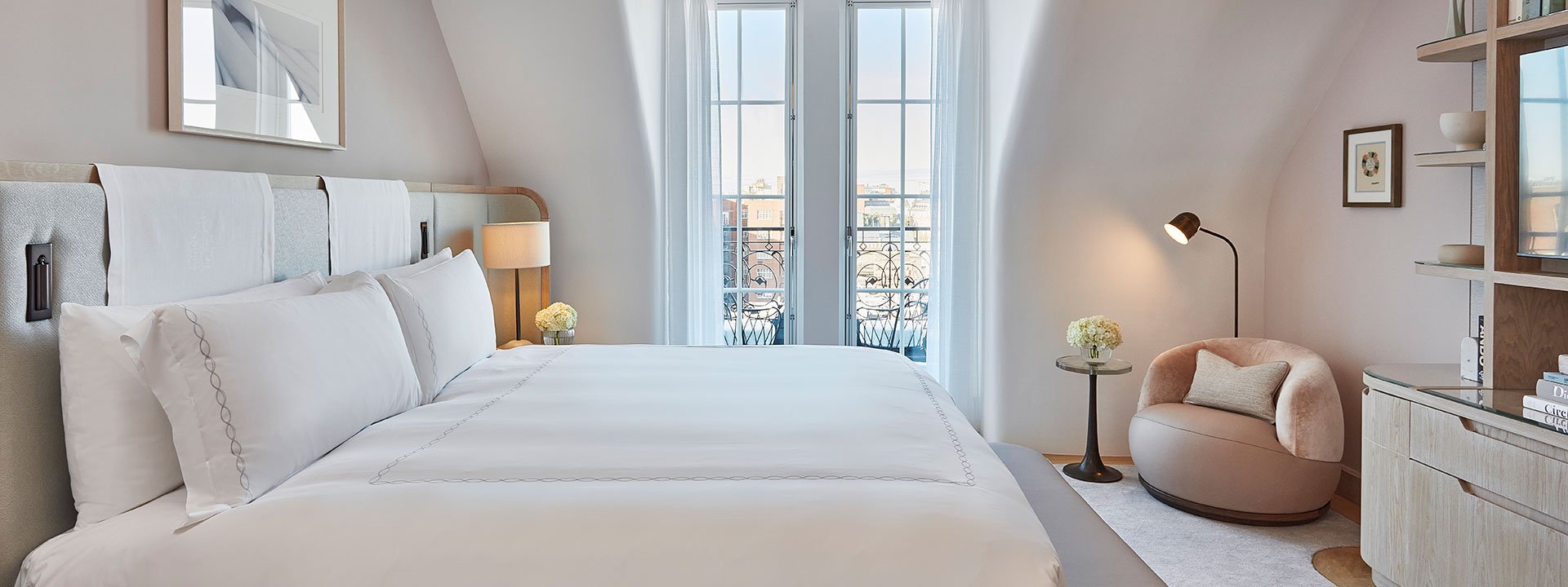 King Bed in the Mayfair Balcony Room, with a comfortable armchair and Art Deco details.