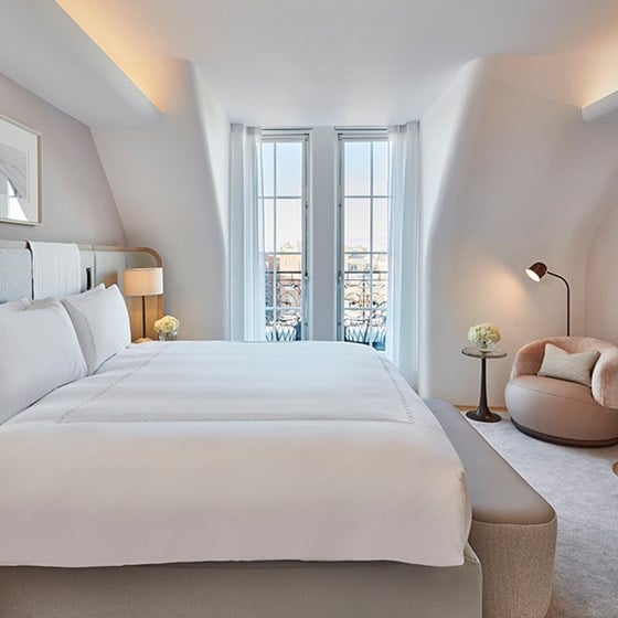 A bright bedroom, with one King Bed, and a comfortable modern corner armchair in a classic interior from Claridge's Hotel.