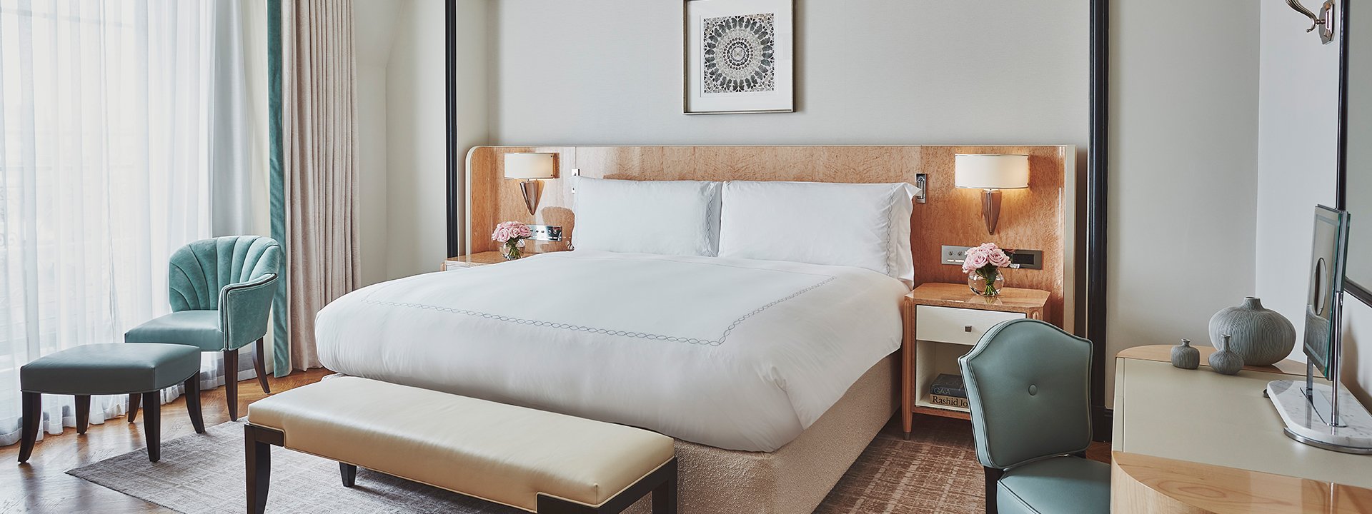 A view of the King Bed in the Mayfair Balcony Room, surrounded by mint green furniture and a beige interior.