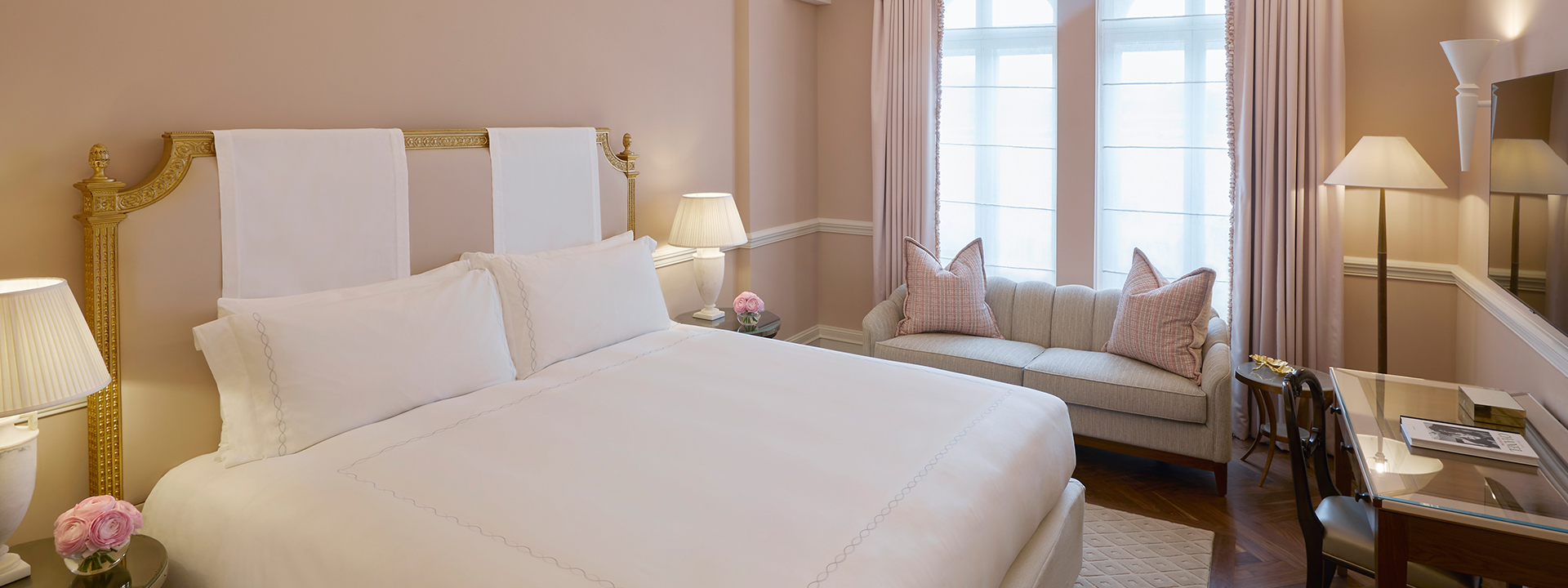 King Bed in the Mayfair Room, surrounded by warm beige colours in the interior, decorated with flower arrangements.