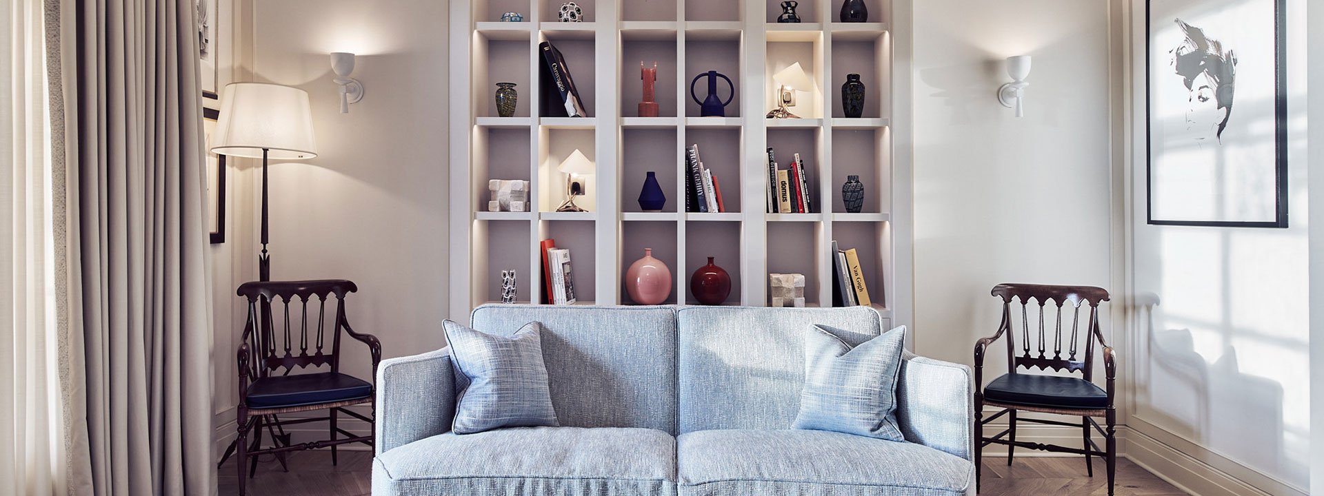 A comfortable sofa and a shelf with details in the background as part of the Mayfair Terrace Suite interior.