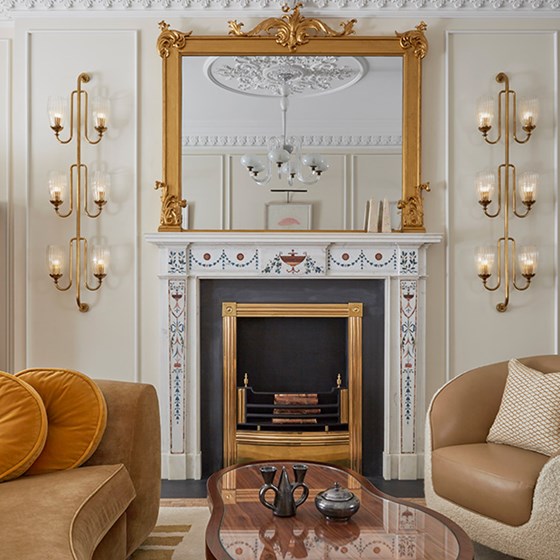 A mirror, a fireplace, and comfortable furniture made of rich materials are part of the interior of the Mayfair Suite.