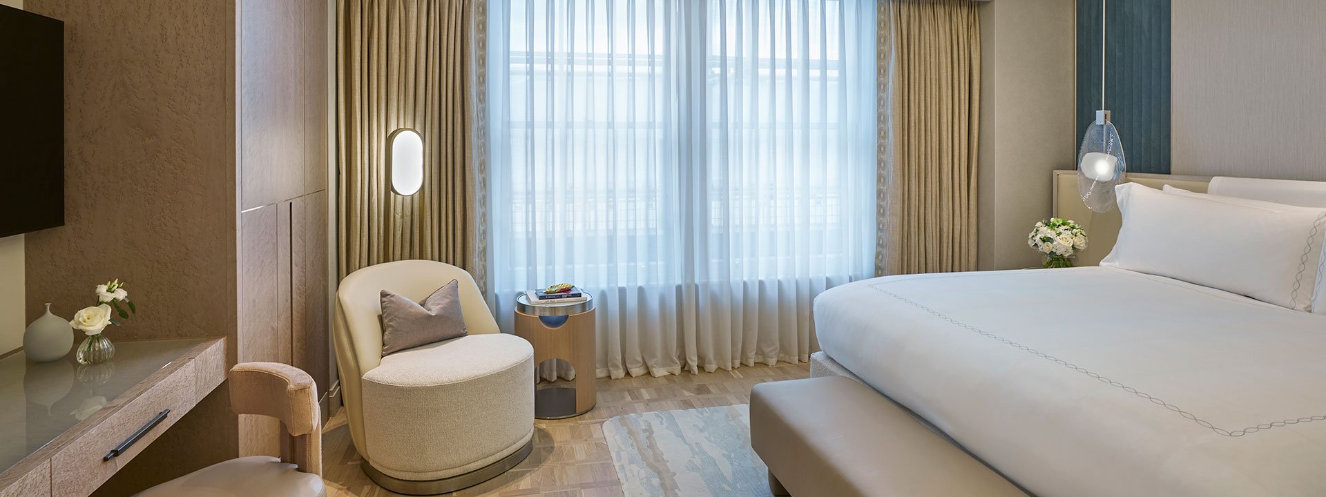 A view of the elegant bedroom of the Mayfair Suite, and a King Bed with an armchair with luxurious elements.