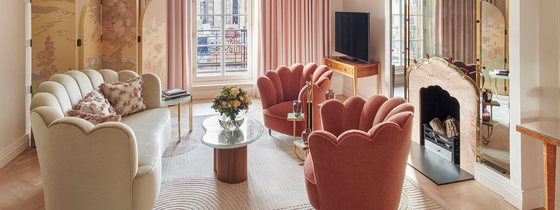 Pink armchairs and a sofa by the fireplace in the sitting room from the Mayfair Terrace Suite.