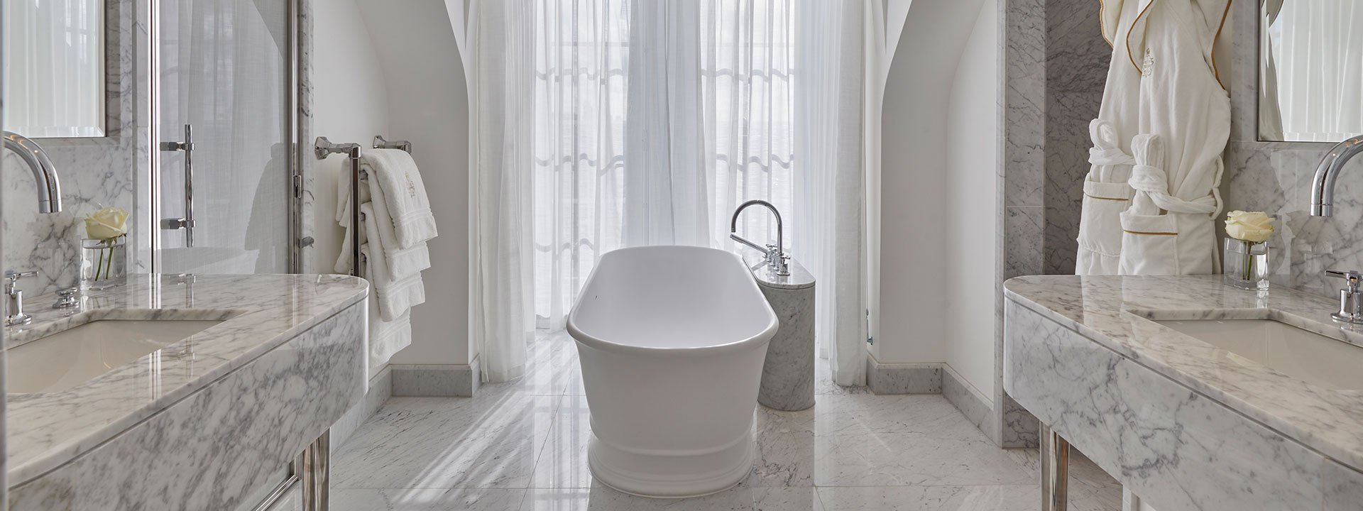 A view of the contemporary marble bathroom, with a central bathtub in the Mayfair Terrace Suite.