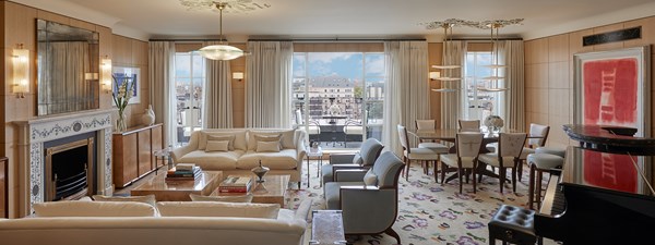 Mews Pavilion at Claridge's - lounge and dining area with couches, armchairs, marble coffee tables, dining table and grand piano. There is a view on the terrace in the background with view on the roofs.