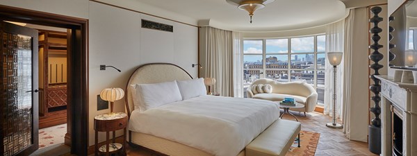 The Mews Pavilion at Claridge's - bedroom view with bed, sofa against the windows, fireplace on the right hand side and dressing room on the left hand side.