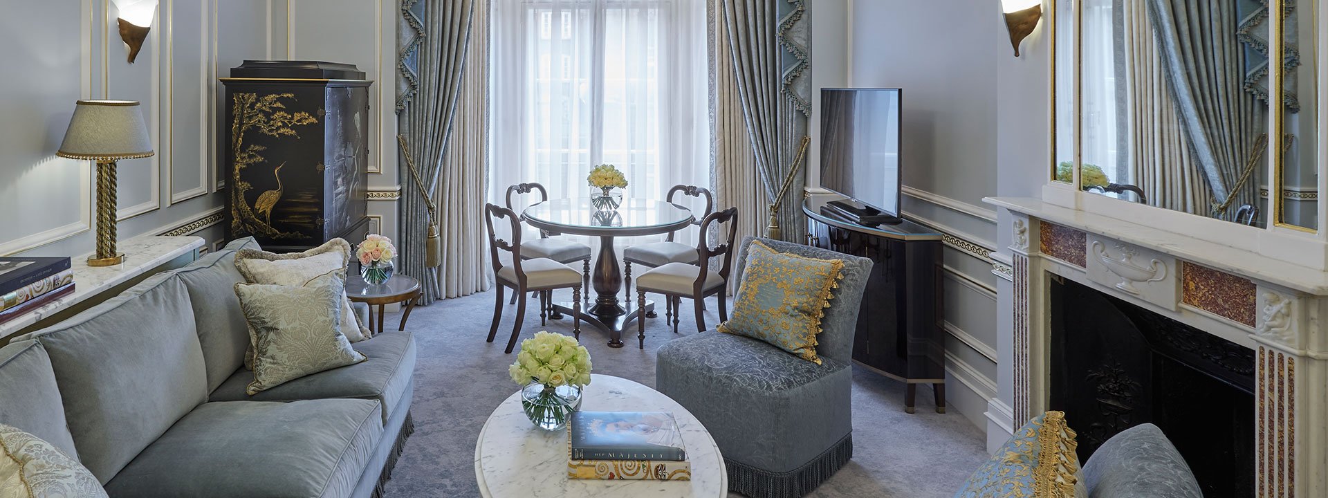 Sitting room with original fireplace in the Mayfair Suite, in grey, soft blue and gold colour palettes.