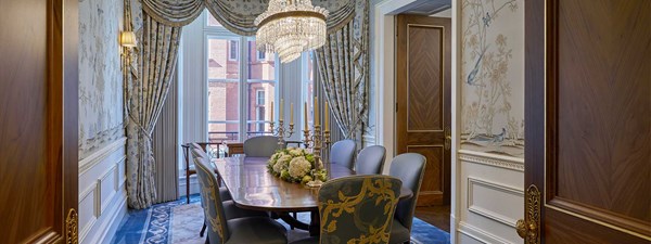 Royal Suite at Claridge's -  Dining table with blue chairs around and window in the back with blue pattern curtains.
