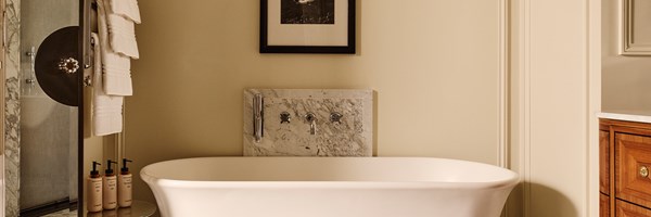 Serene bathroom with white freestanding bathtub, marble fittings, towel rail, and walk-in shower with glass door.