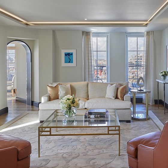 Elegant interior design, comfortable furniture, and glass table in The Mayfair Pavilion Suite at Claridge's Hotel.