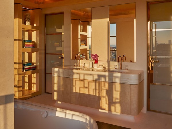 bathroom with golden hour sun shining through and creating shadows on the double basins and mirrors