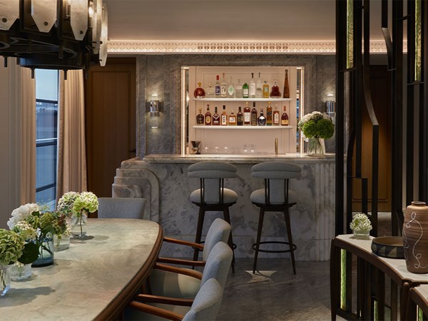 Dimly lit bar with tall grey barstools around the edge in a suite