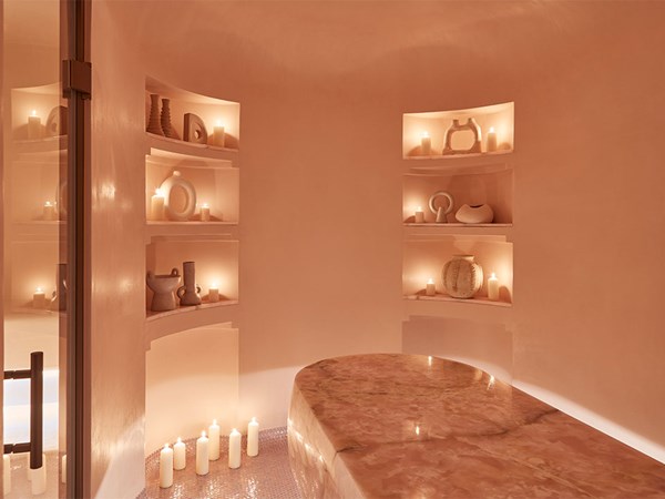 pink room featuring pink onyx bed, lit candles, shelves and pink coloured ornaments. A very serene scene atmosphere is depicted.