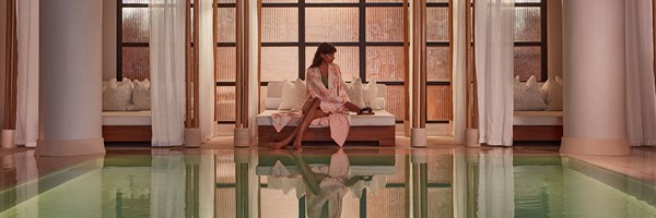 Claridge's swimming pool and woman in pink patterned kimono on cream bed with pot of tea