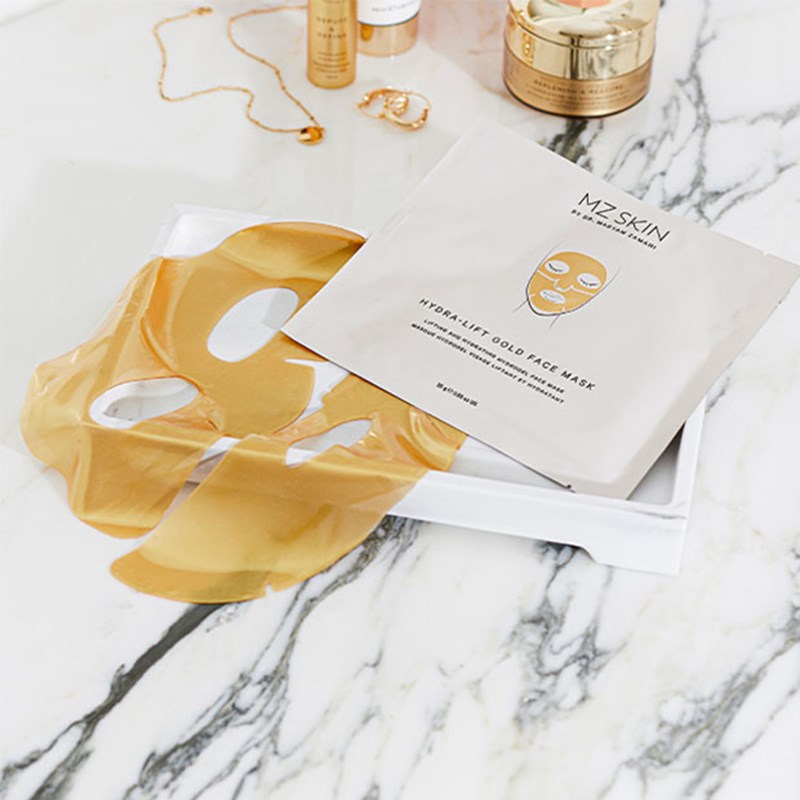 Gold MZ face mask and branded packaging on a marble table.