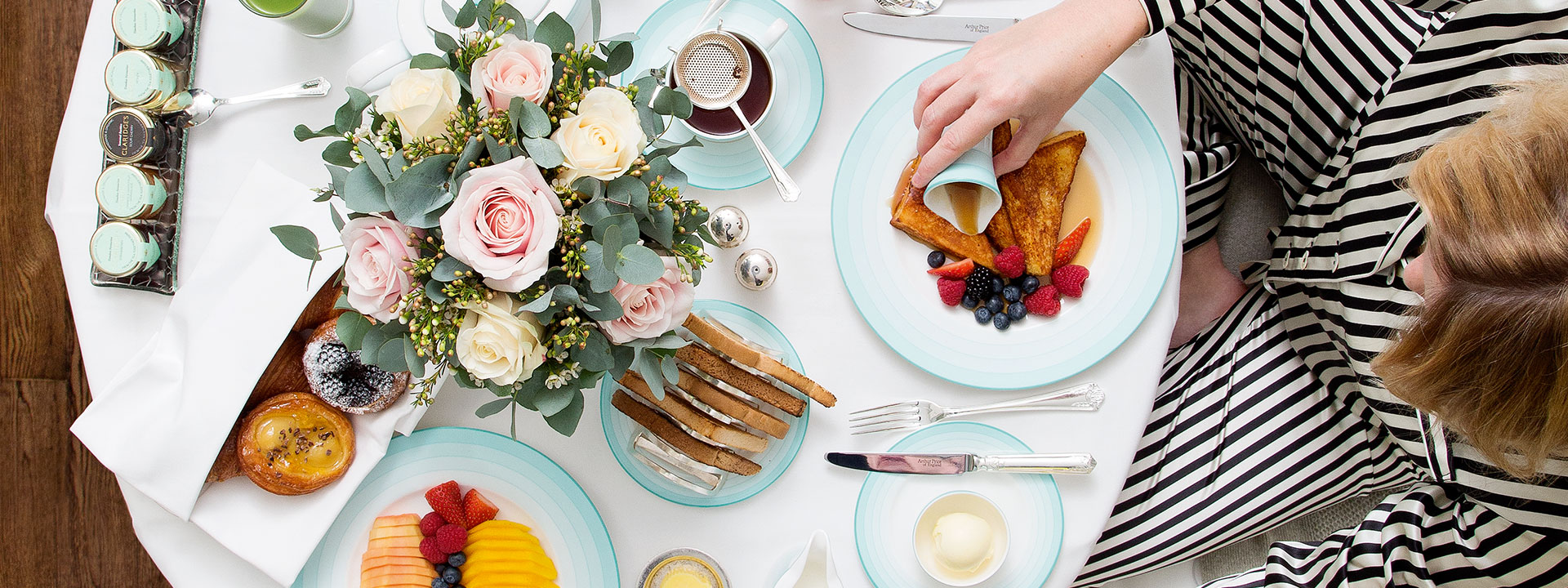 Breakfast with toast, fruit, pastries, and a beautiful bouquet arrangement with morning coffee.