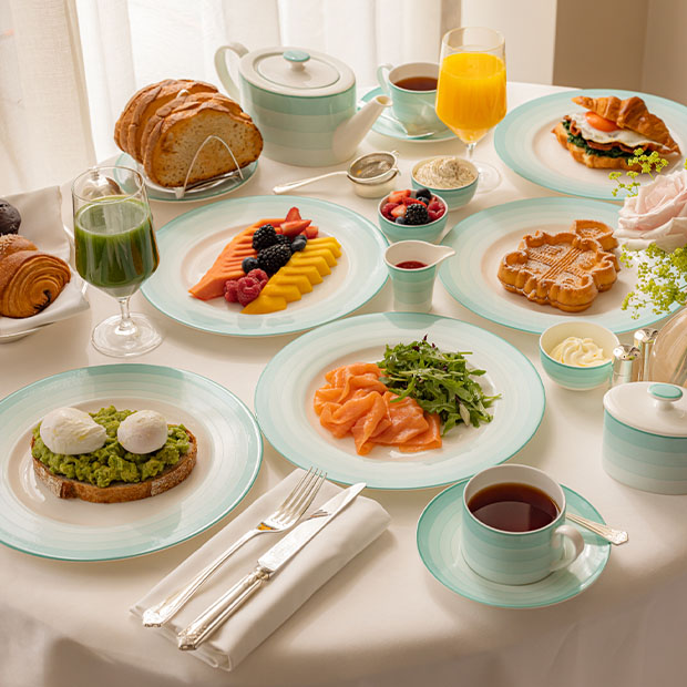 Table set with fruit, pastries, avocado toast, smoked salmon, juices and tea.