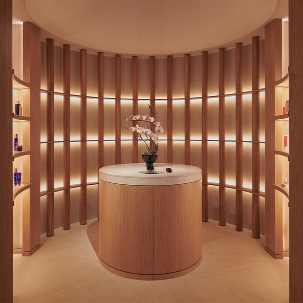 Curved wood-paneled spa retail space with softly lit shelves and a central display counter.